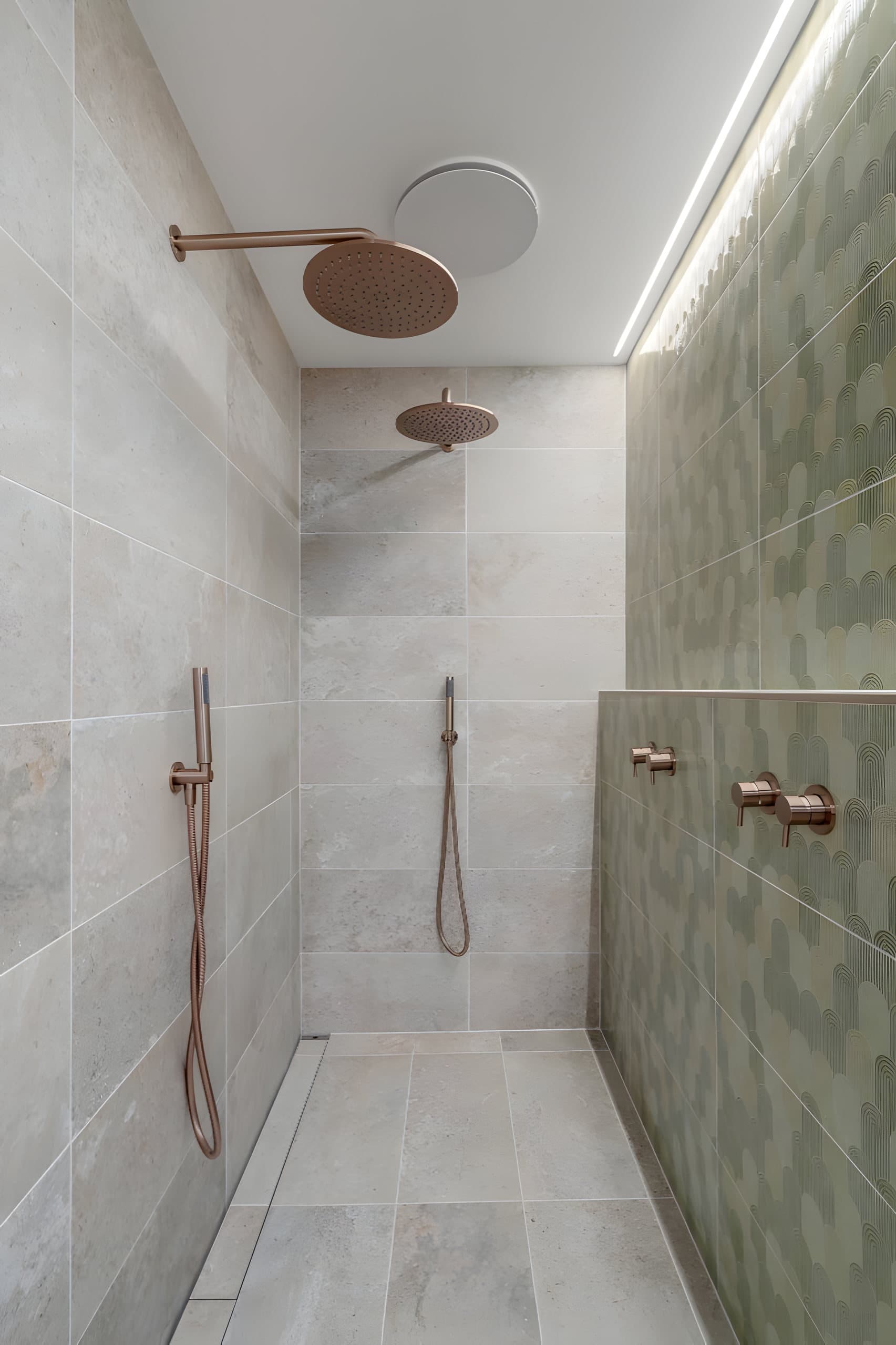 Double shower with copper rain heads and green feature wall