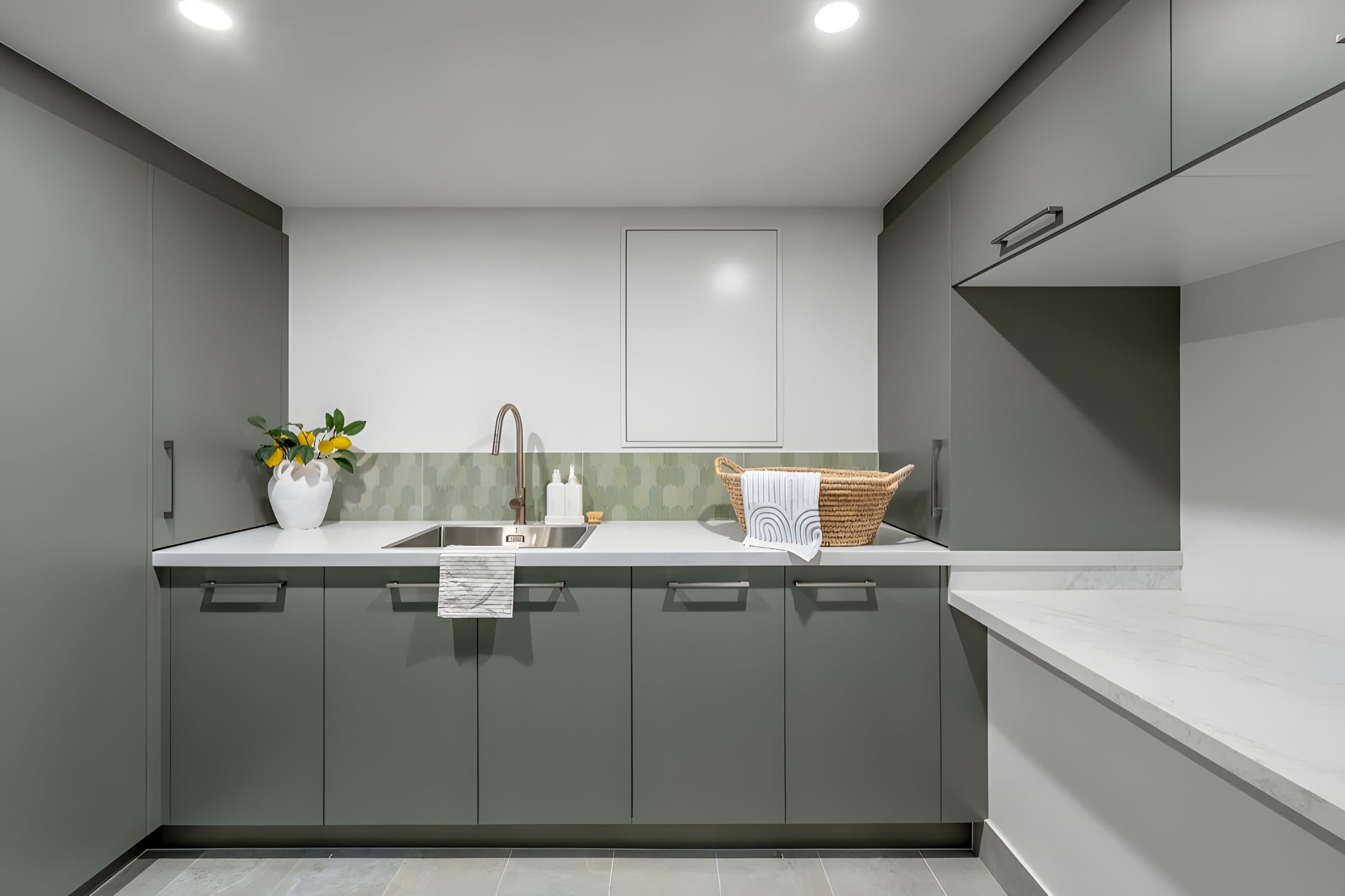 Sage green laundry cabinets with stone bench