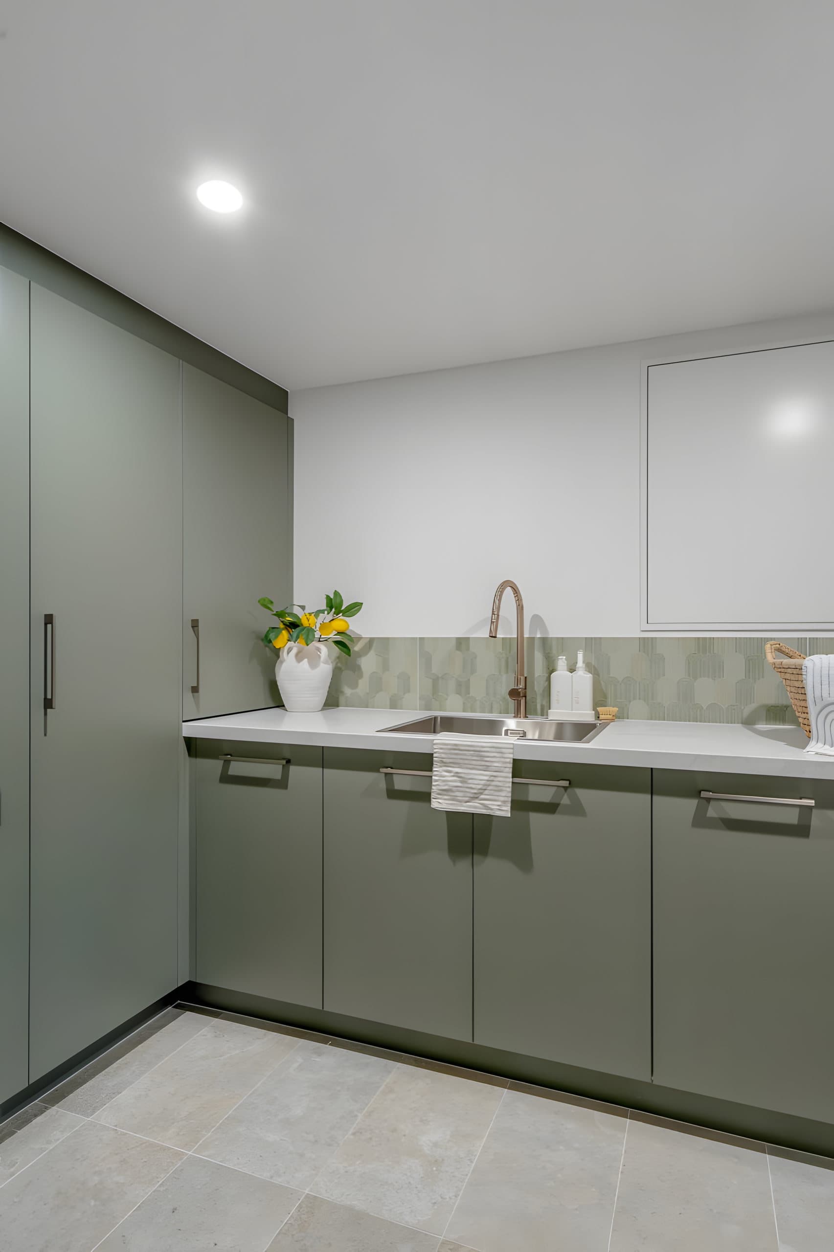Laundry with sage cabinets, copper tap and feature splashback