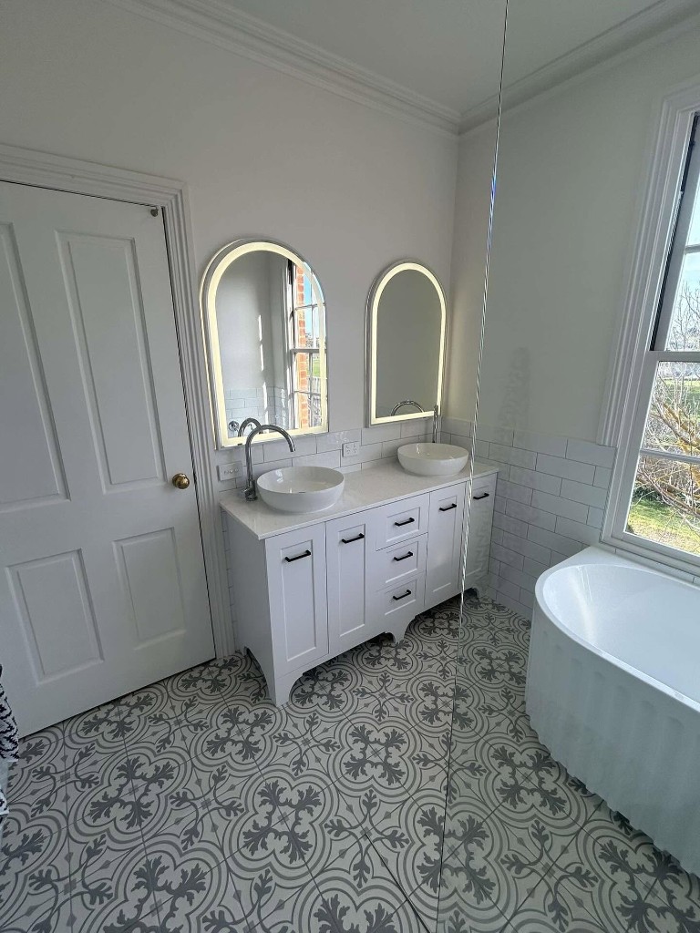 Double vanity with arched backlit mirrors